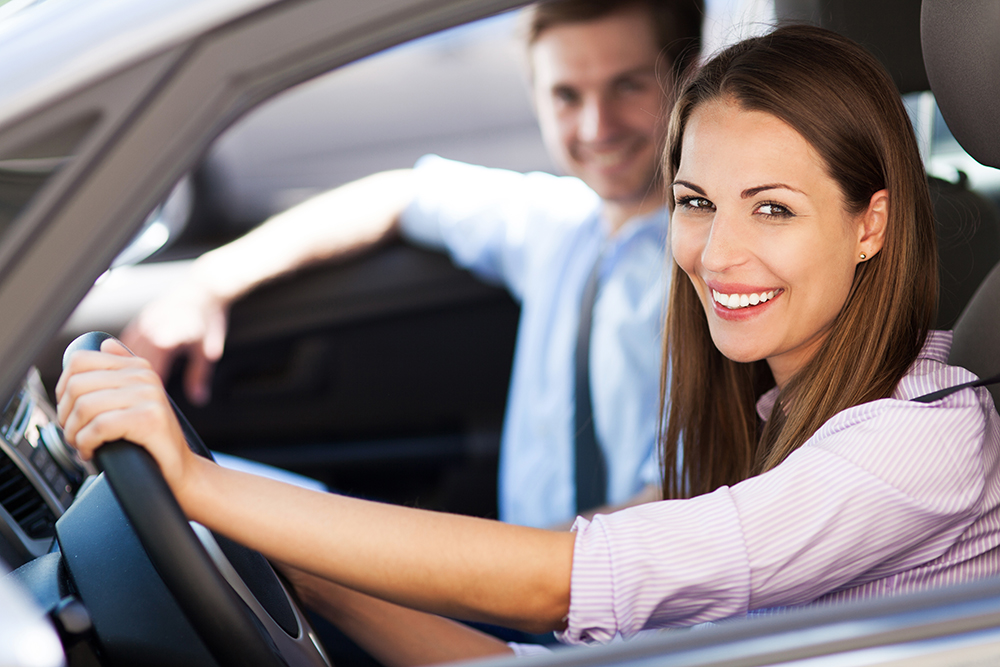 man and woman sitting in car smiling out window