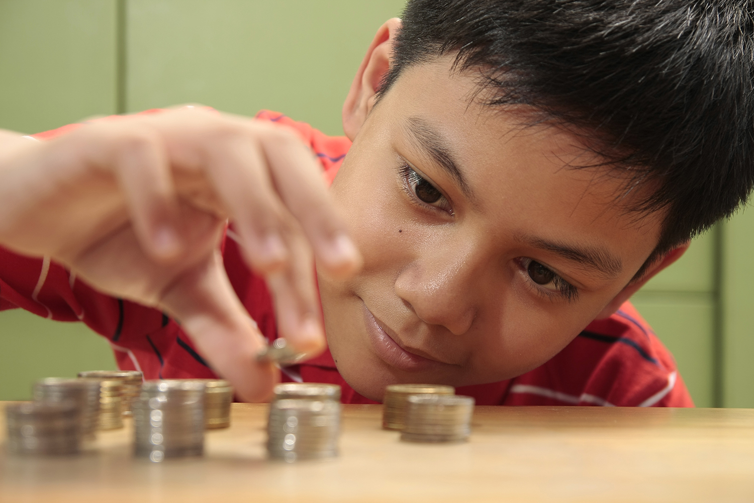 A photo of a boy stacking a pile of coins