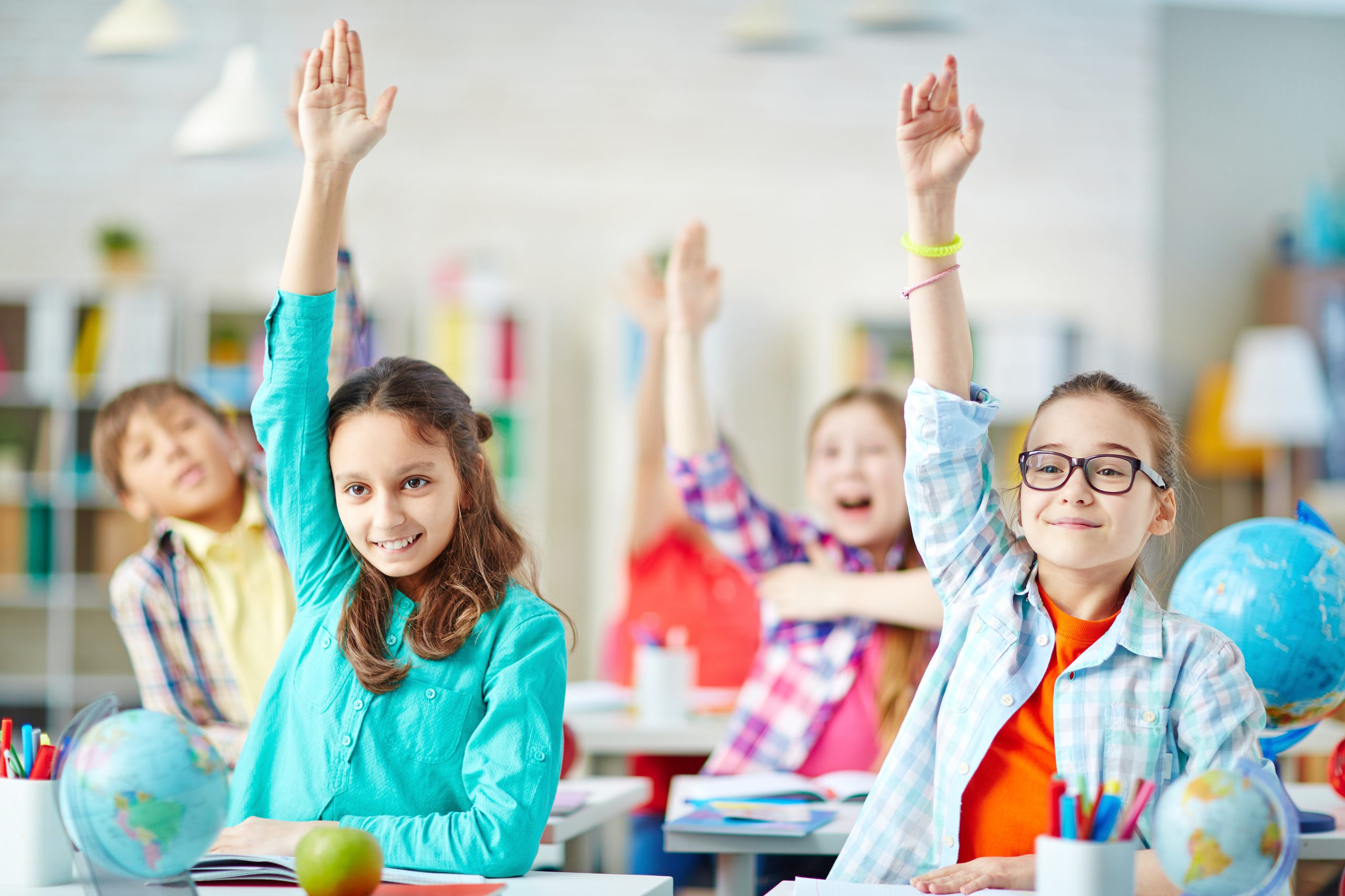 classroom of kids raising hands